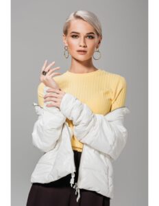 persona modelando una chaqueta blanca, buso amarillo y un pantalon negro