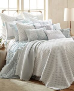 cama con muchas almuedas y mesa de noche con lampara