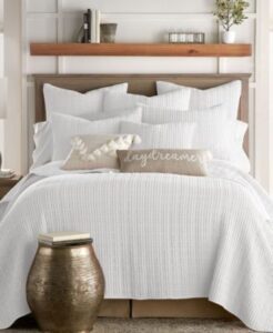 cama con muchas almuedas y mesa de noche con lampara