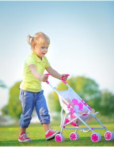 una niña pequeña manejando un coche de bebes de jueguete