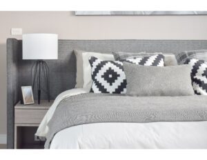 cama moderna com cobijas almuadas y con una mesa con una lampara de mesa