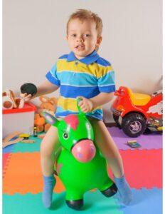 un bebe sobre un caballo de pastico en una sala de juegos