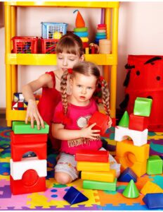 dos niñas jugando con piezas de construcción de juguete