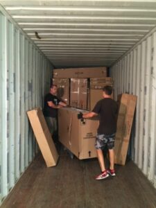 dos personas descargando una caja grander dentro de un contenedor