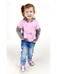una niña con un buso rojado y morado con un jean modelando